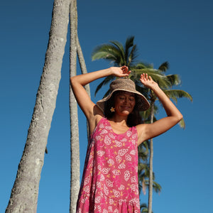 women with brown hair wearing a mini dress with shells and pua print in pink