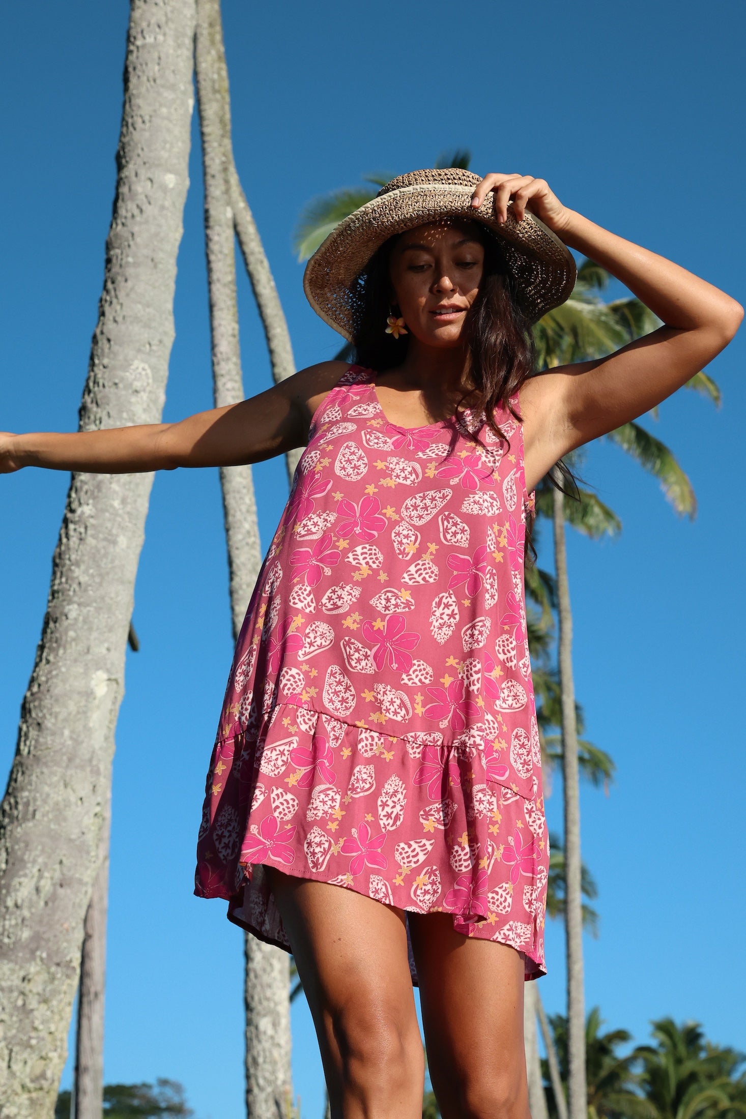 women with brown hair wearing a mini dress with shells and pua print in pink