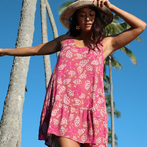 women with brown hair wearing a mini dress with shells and pua print in pink