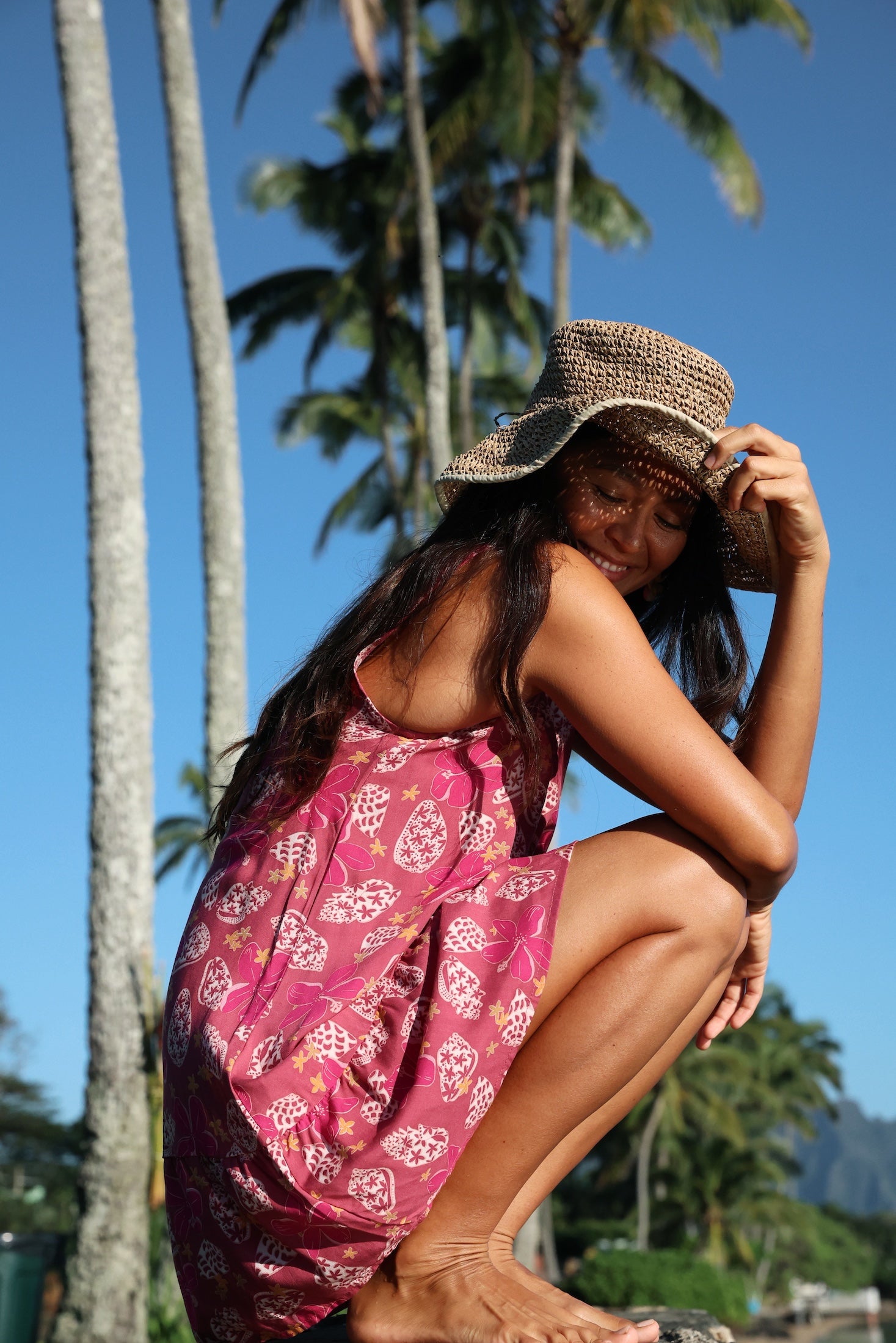 women with brown hair wearing a mini dress with shells and pua print in pink