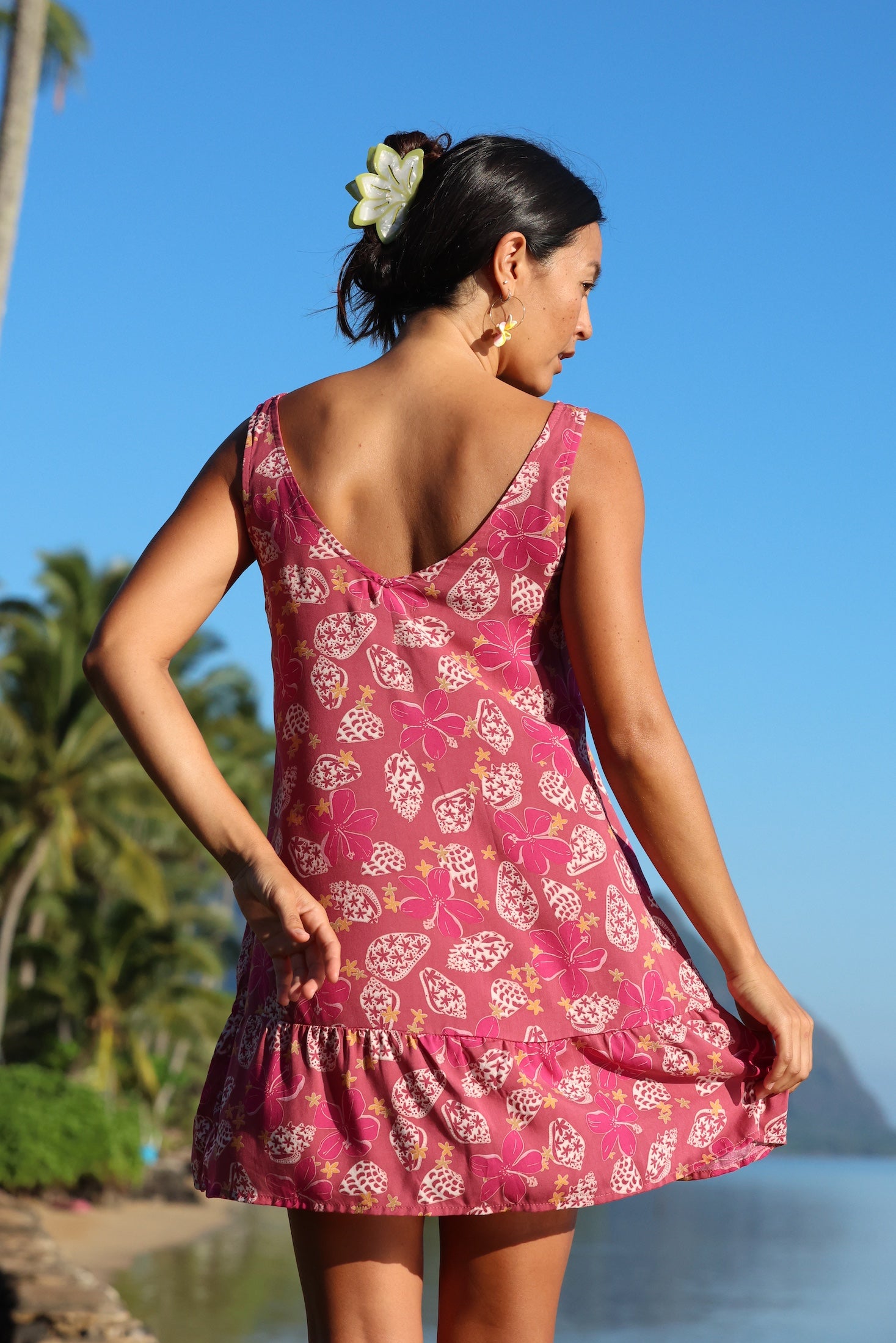 women with brown hair wearing a mini dress with shells and pua print in pink