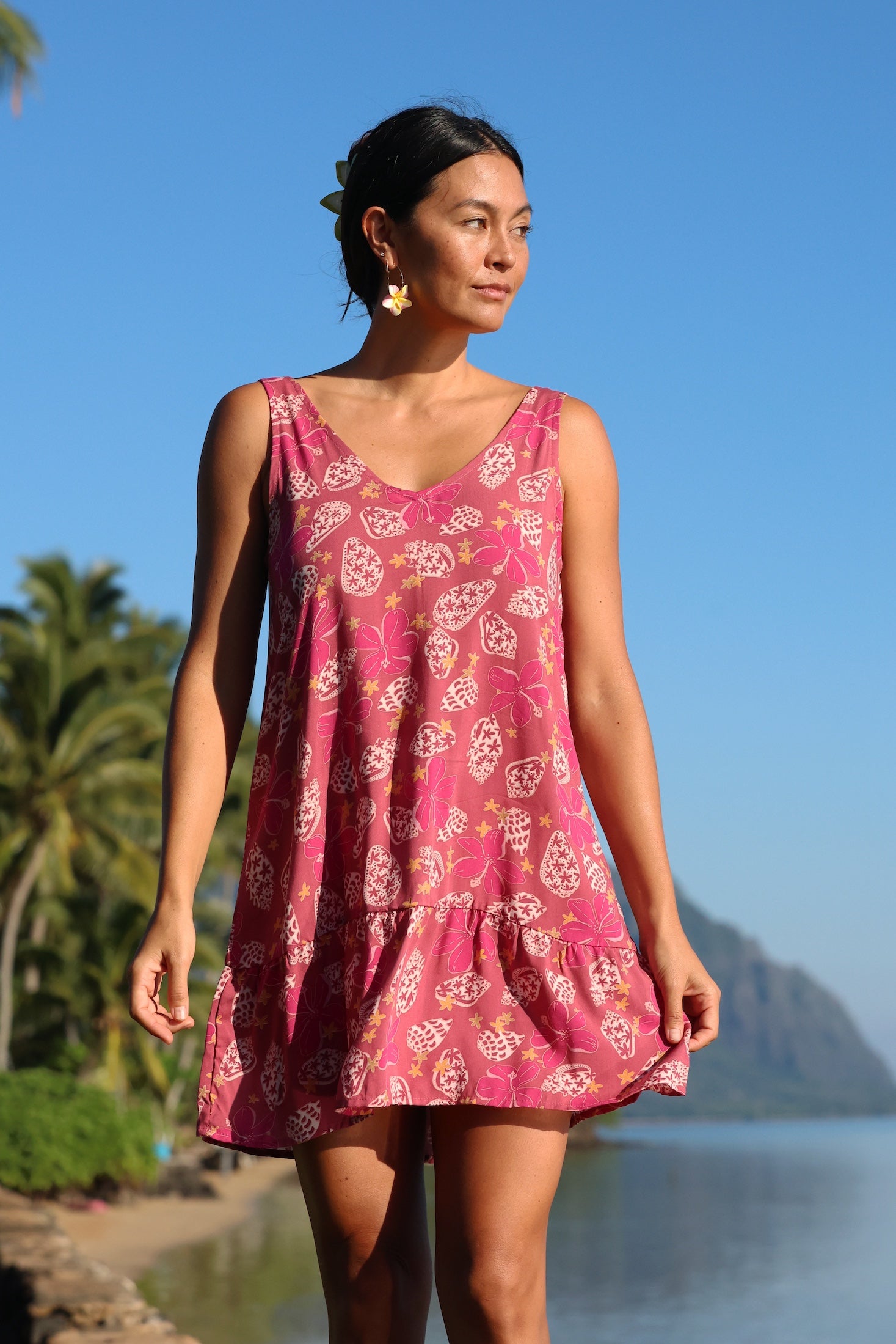 women with brown hair wearing a mini dress with shells and pua print in pink