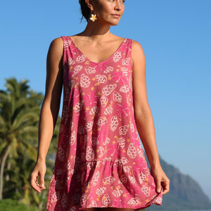 women with brown hair wearing a mini dress with shells and pua print in pink