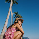 women with brown hair wearing a mini dress with shells and pua print in pink