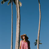 women with brown hair wearing a mini dress with shells and pua print in pink