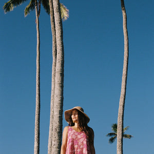 women with brown hair wearing a mini dress with shells and pua print in pink