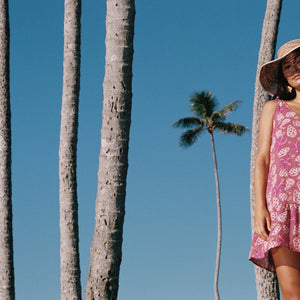 women with brown hair wearing a mini dress with shells and pua print in pink