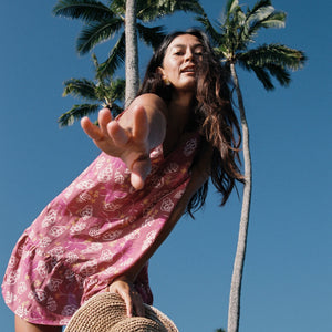 women with brown hair wearing a mini dress with shells and pua print in pink