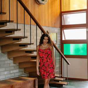 woman with brown hair wearing a spaghetti strap mini slip dress with retro pink pua print