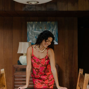 woman with brown hair wearing a spaghetti strap mini slip dress with retro pink pua print