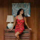 woman with brown hair wearing a spaghetti strap mini slip dress with retro pink pua print