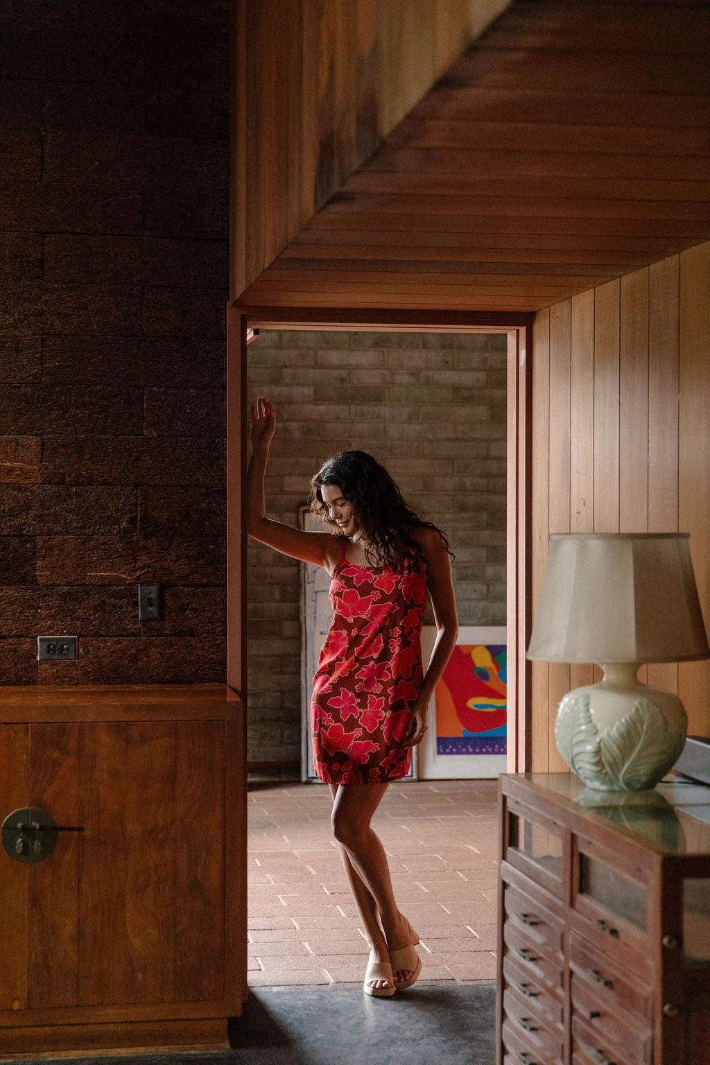 woman with brown hair wearing a spaghetti strap mini slip dress with retro pink pua print