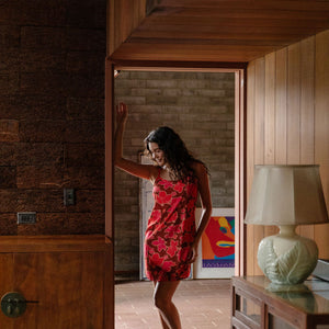 woman with brown hair wearing a spaghetti strap mini slip dress with retro pink pua print