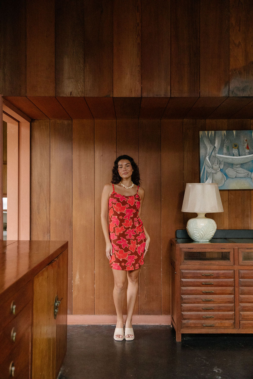 woman with brown hair wearing a spaghetti strap mini slip dress with retro pink pua print