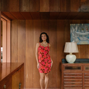 woman with brown hair wearing a spaghetti strap mini slip dress with retro pink pua print