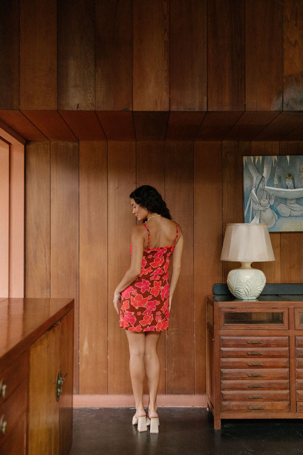 woman with brown hair wearing a spaghetti strap mini slip dress with retro pink pua print