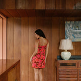 woman with brown hair wearing a spaghetti strap mini slip dress with retro pink pua print