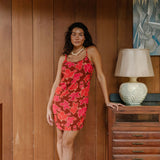 woman with brown hair wearing a spaghetti strap mini slip dress with retro pink pua print