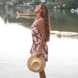Woman with brown hair wearing a simple slip dress with scoop neck in blush and brown hibiscus print