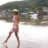 Woman with brown hair wearing a simple slip dress with scoop neck in blush and brown hibiscus print