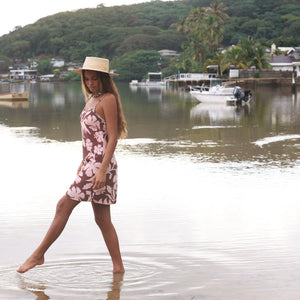 Woman with brown hair wearing a simple slip dress with scoop neck in blush and brown hibiscus print