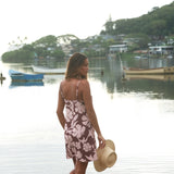 Woman with brown hair wearing a simple slip dress with scoop neck in blush and brown hibiscus print