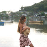 Woman with brown hair wearing a simple slip dress with scoop neck in blush and brown hibiscus print