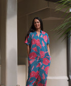 Woman wearing long blue dress with large pink and red floral print.