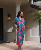 Woman wearing long blue dress with large pink and red floral print.