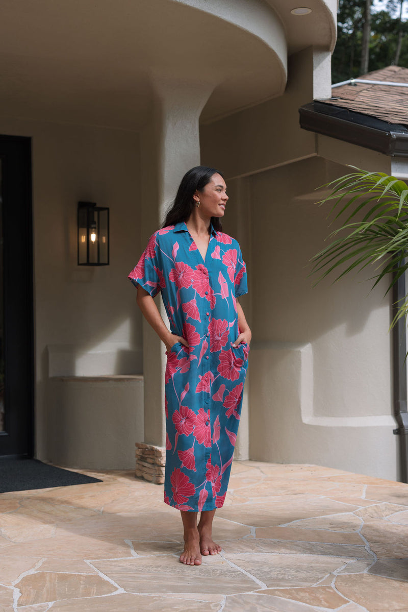 Woman wearing long blue dress with large pink and red floral print.