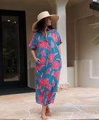 Woman wearing long blue dress with large pink and red floral print.