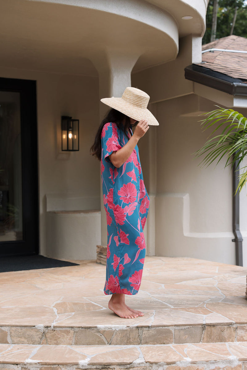 Woman wearing long blue dress with large pink and red floral print.