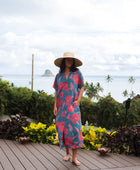 Woman wearing long blue dress with large pink and red floral print.