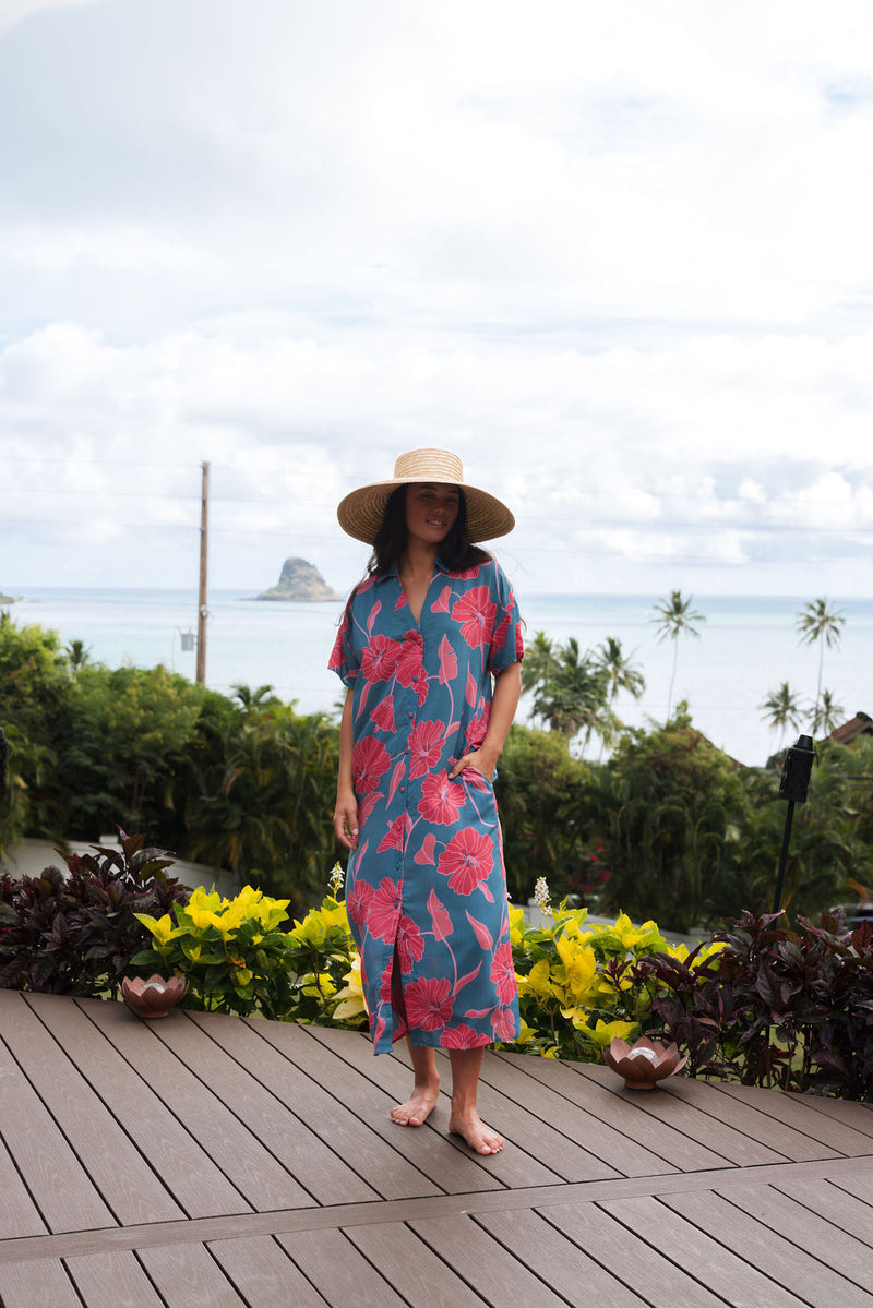 Woman wearing long blue dress with large pink and red floral print.