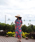 Woman wearing long blue dress with large pink and red floral print.