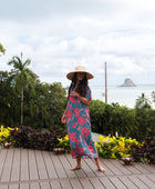 Woman wearing long blue dress with large pink and red floral print.