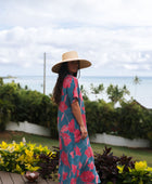 Woman wearing long blue dress with large pink and red floral print.