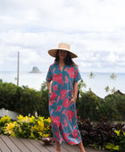 Woman wearing long blue dress with large pink and red floral print.