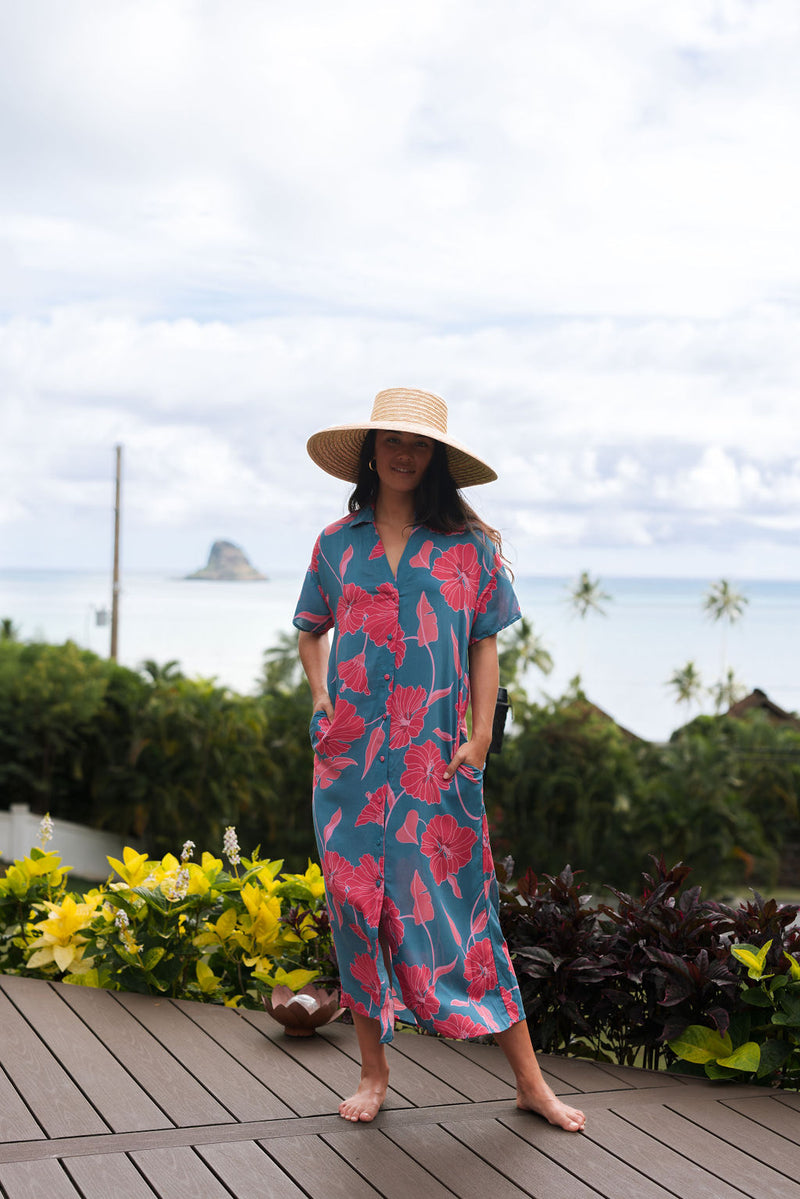 Woman wearing long blue dress with large pink and red floral print.