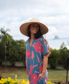 Woman wearing long blue dress with large pink and red floral print.