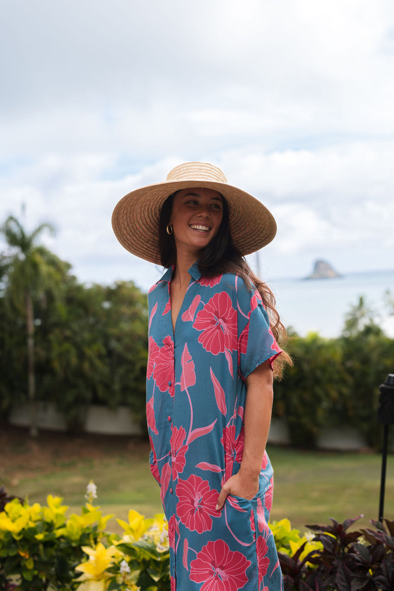 Woman wearing long blue dress with large pink and red floral print.