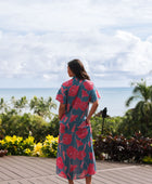 Woman wearing long blue dress with large pink and red floral print.