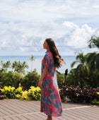 Woman wearing long blue dress with large pink and red floral print.