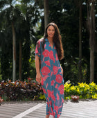 Woman wearing long blue dress with large pink and red floral print.