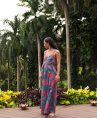 Woman wearing long blue sleeveless jumpsuit with large pink and red floral print.