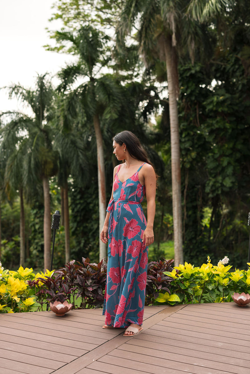 Woman wearing long blue sleeveless jumpsuit with large pink and red floral print.