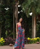 Woman wearing long blue sleeveless jumpsuit with large pink and red floral print.