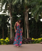 Woman wearing long blue sleeveless jumpsuit with large pink and red floral print.