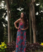 Woman wearing long blue sleeveless jumpsuit with large pink and red floral print.