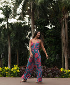 Woman wearing long blue sleeveless jumpsuit with large pink and red floral print.